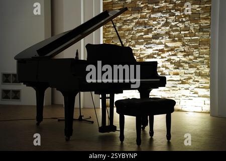 Grand piano in a room with a brick wall and a wooden floor Stock Photo