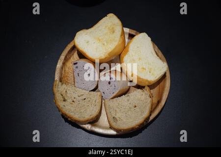 Slices of bread in a wooden plate on a black background Stock Photo