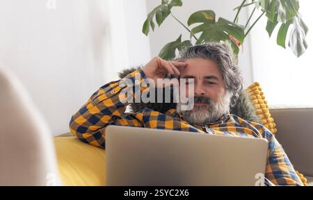 Focused mature man working from home on laptop computer Stock Photo