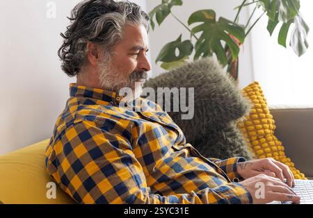Smiling bearded man working from home on laptop computer Stock Photo