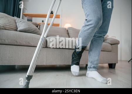 Close up view of legs. Man with crutches is at home indoors. Having injuries. Stock Photo