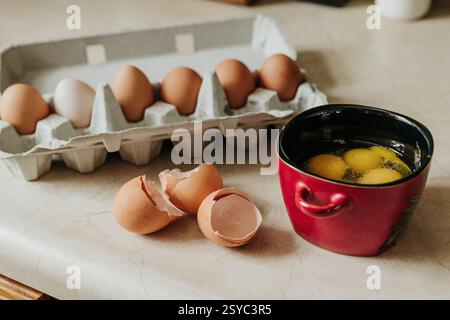 Fresh eggs cracked into bowl with eggshells laying next to it Stock Photo