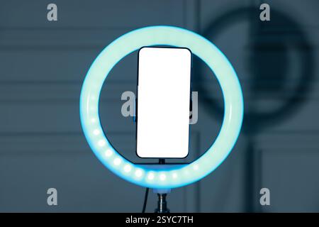Ring lamp with smartphone against wall indoors Stock Photo