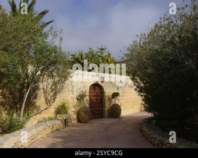 Traditional Stone Wall and Courtyard Path with Wooden Doorway in Garden Setting Stock Photo