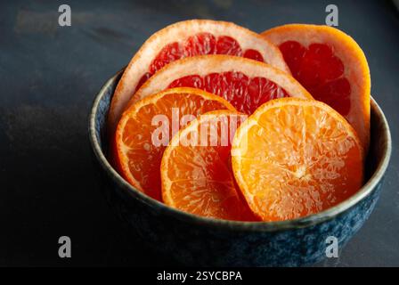 A refreshing and vibrant display of sliced juicy oranges and grapefruit arranged in a beautifully designed blue decorative bowl. Stock Photo