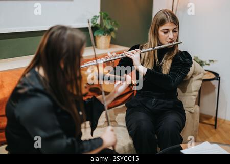Two young musicians rehearsing together on flute and violin indoors Stock Photo