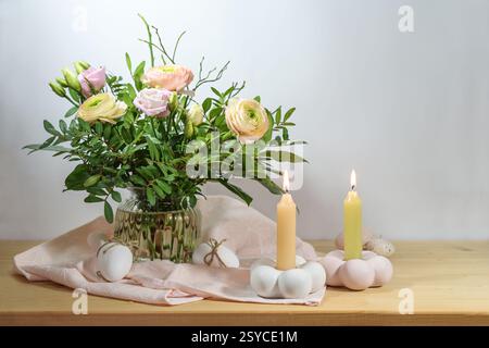 Easter decoration with a flower bouquet, Easter eggs and candles in soft pink and apricot colors on a wooden sideboard, copy space, selected focus, na Stock Photo