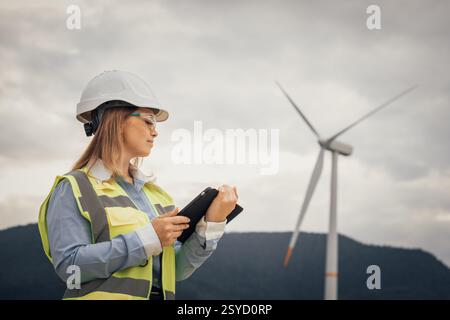 A skilled female engineer is diligently inspecting a wind turbine at a renewable energy site, focusing on ensuring safety, sustainability, and Stock Photo
