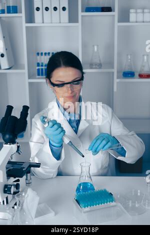 A scientist conducts a lab experiment using a micropipette and glassware for precise measurements in biochemistry, microbiology, and healthcare, while Stock Photo