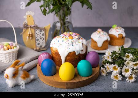 Easter kulich with candied fruits in white glaze with colorful sprinkles and painted eggs. Traditional Easter pastry. Easter holiday. Close-up, select Stock Photo