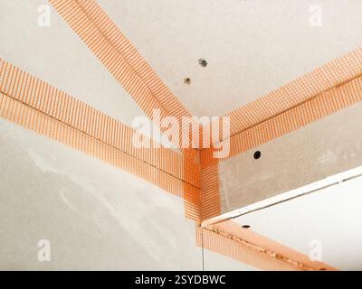Tape on the joints of plasterboards on the walls and ceiling of a house extension in preparation for plastering Stock Photo