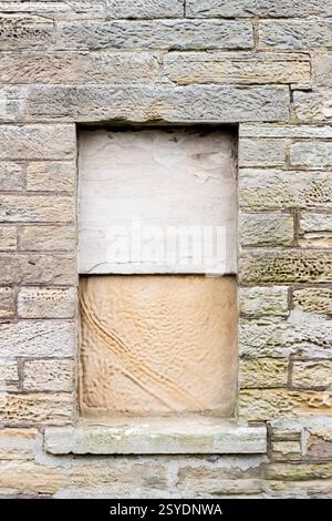 Window in old house sealed up with stone slabs. Stock Photo