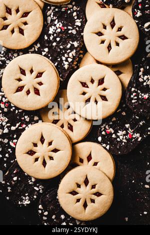 A festive assortment of snowflake Linzer cookies with raspberry jam and dark chocolate peppermint bark, creating am elegant holiday dessert spread. Stock Photo