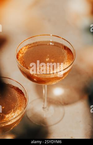 A sparkling golden cocktail in a textured coupe glass, glowing in warm light—perfect for a celebration or golden hour toast. Stock Photo
