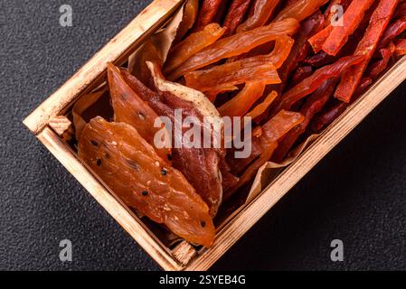 Jerky, dried fish in the form of sticks with salt, spices and herbs on a dark concrete background Stock Photo