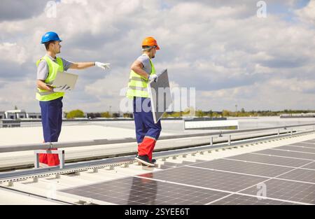 Electricians On Roof Repairing, Installing, Or Maintaining Solar Panels Stock Photo