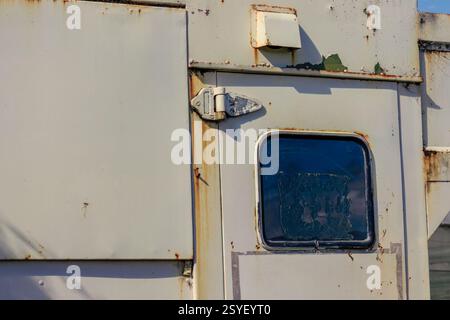 Close-up photography of the window of the door of an old rusty campervan, illuminated by the afternoon sun, in a farm  in the eastern Andean mountains Stock Photo