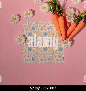 Easter pattern made with carrots and flowers on pastel pink background. Creative minimal holiday concept. Copy space Stock Photo