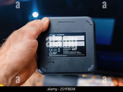 Paris, France - Feb 17, 2025: A person holds an Orange TV Decoder TV 6 by Sagemcom, showing its black casing with branding, technical specifications, Stock Photo