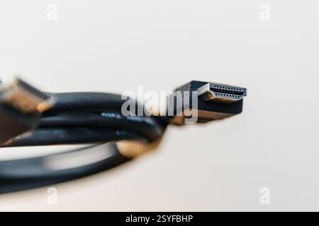 A close-up macro shot of an HDMI connector showing its metallic pins and black plastic housing, with the coiled cable visible in the background. Stock Photo