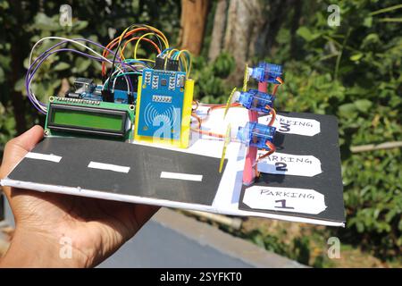 Working model of an RFID based smart parking system that uses programmable microcontroller and servo for its functioning held in the hand Stock Photo