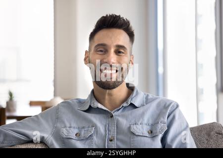 Man looking at camera with joyful expression seated on couch Stock Photo