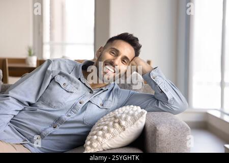 Young Latin man resting reclining on comfortable couch Stock Photo