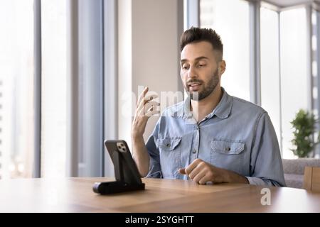 Serious Hispanic man speaking to client through videocall Stock Photo
