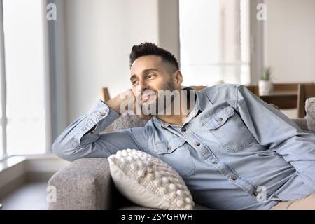 Hispanic man relaxing leaning on comfortable sofa in contemporary room Stock Photo