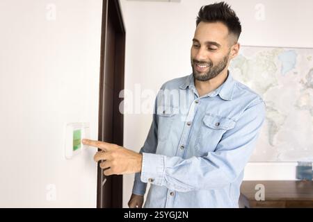 Man adjusts settings, switch on thermostat or smart control panel Stock Photo
