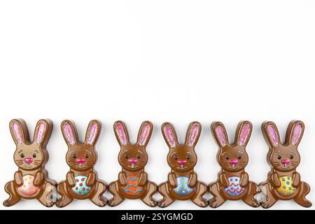 Six Easter bunnies with colourful eggs arranged evenly next to each other on a white background Stock Photo