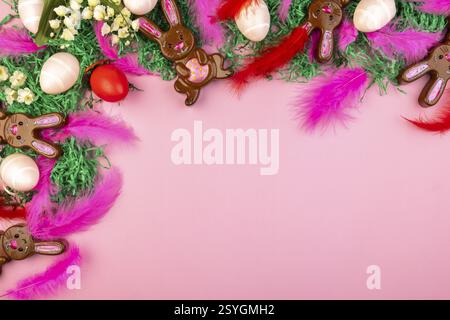 Easter bunnies and colourful eggs on a pink background with flowers and feathers Stock Photo