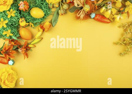 Yellow background with natural decorations such as flowers, Easter eggs and carrots Stock Photo