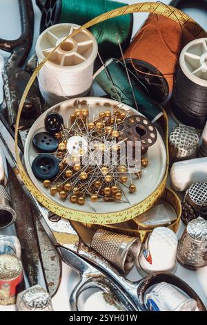 Sewing needles stuck in a green miniature spools thread Steel scissors, Spools of thread of various colour, Thimbles and Measuring tape including Pins Stock Photo