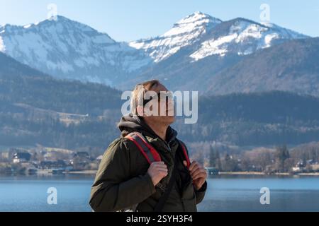 An elderly hiker enjoys nature on a cold day by the lake. Stock Photo