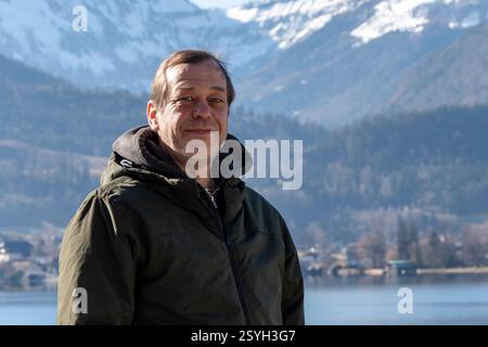 Portrait of a man 50-55 years old in a warm jacket on the background of a mountain landscape and a lake Stock Photo