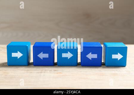 Blue cubes with arrows pointing in different directions on wooden table Stock Photo
