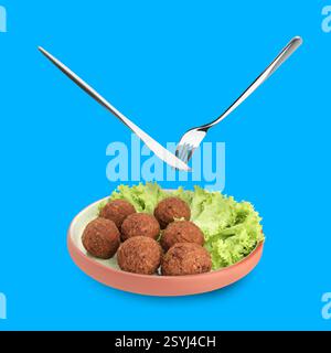 Cutlery in air over plate with delicious falafel balls on blue background Stock Photo