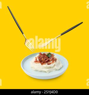 Cutlery in air over plate with mashed potato on golden background Stock Photo