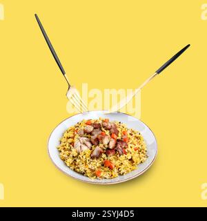 Cutlery in air over plate with delicious pilaf on pastel yellow background Stock Photo