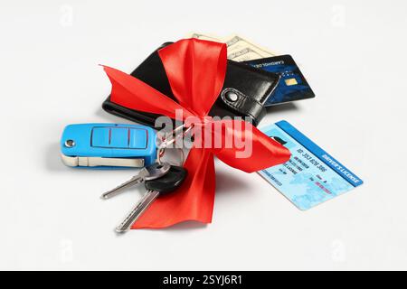 Gift keys of new car with red bow, wallet, driver license and credit card on white background Stock Photo