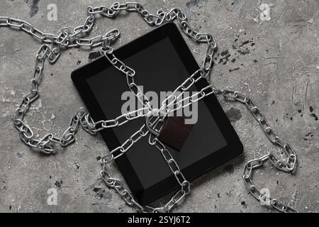 Tablet computer with padlock and chains on grunge background. Cyber security concept Stock Photo