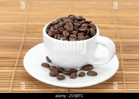 A white ceramic mug filled with roasted coffee beans gives off a rich aroma. Stock Photo