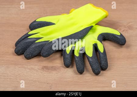 Pair of yellow carpenter's gloves, on wood Stock Photo