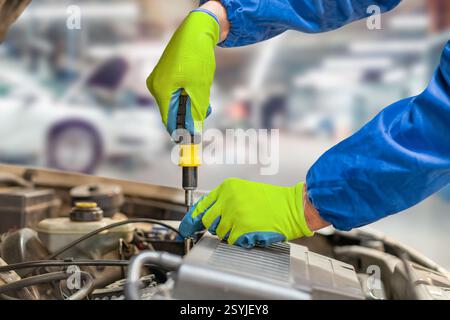 Car mechanic hands and screwdriver tools working on automobile performance. Young man motor technician, repair service and maintenance vehicle machine Stock Photo