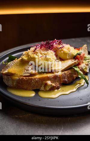 Savory Eggs Benedict featuring Smoked Chicken, Tomato, Rich Sauce, Vegetables atop Sourdough Bread, Breakfast Culinary Delight Concept Stock Photo