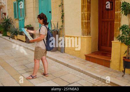 Woman traveler exploring touristic town Birgu on Malta island with a map Stock Photo
