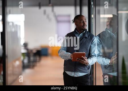 A confident, mature businessman in his 40s-50s using a tablet in a modern office. He is engaged in digital finance management, leveraging technology Stock Photo