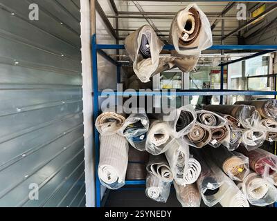 Various fabric rolls are arranged on metal shelves displayed in a modern storage area. Stock Photo