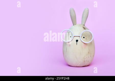 Cute funny egg shaped Easter bunny with glasses on pink background with copy sapce Stock Photo